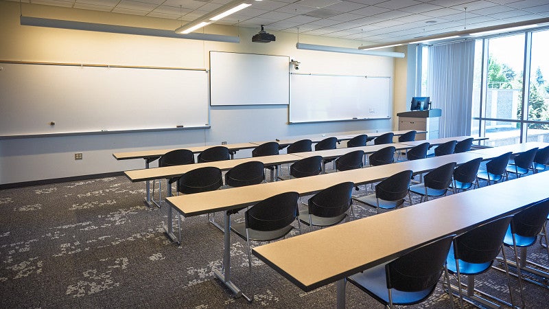 Room 301 set with rows of tables facing three white boards. 