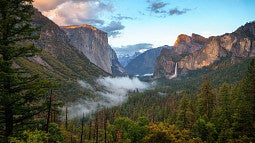 Scenic view of Yosemite National Park that shows mountains, trees and blue sky.