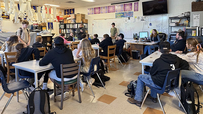 Classroom filled with students sitting and a few standing