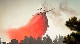 A large air tanker drops red fire retardant on an Oregon wildfire