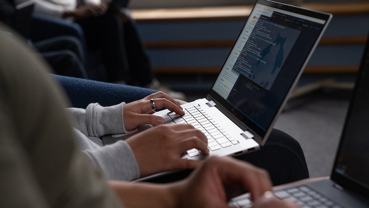 student with laptop open on lap during computer science class