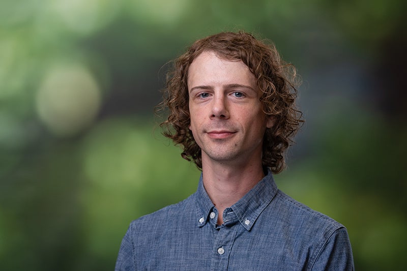 Man with curly brown hair wearing a blue denim shirt