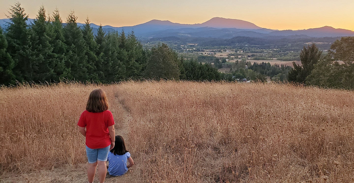 Two young girls look out at the sunset view of Marys Peak