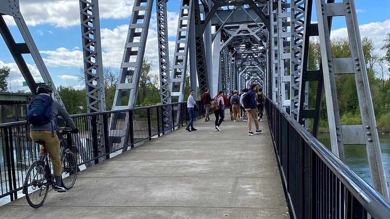 Person bikes over bridge as student group explores