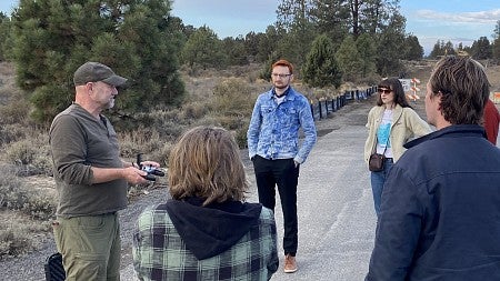 Students and faculty stand on road and converse with each other 