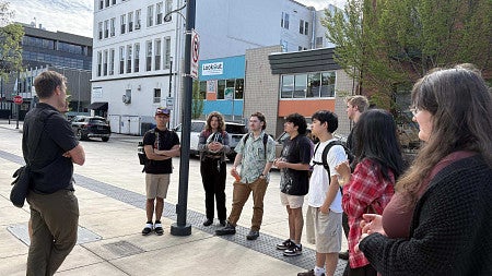 Students listen to professor as he shows them around Downtown Eugene