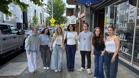 Students pose in front of a Downtown Eugene pawn shop