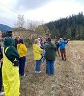 Group of students stand in field and listen to instructor