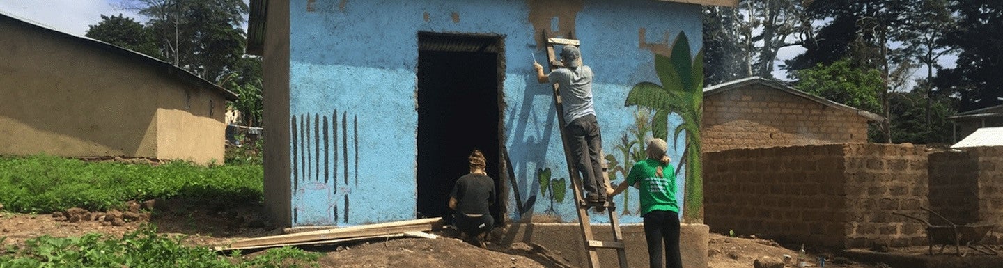 Three people painting and repairing the exterior of a building