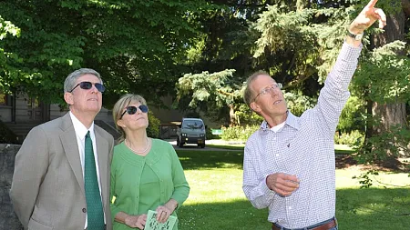 a person points to a tree while then president and first lady of UO look