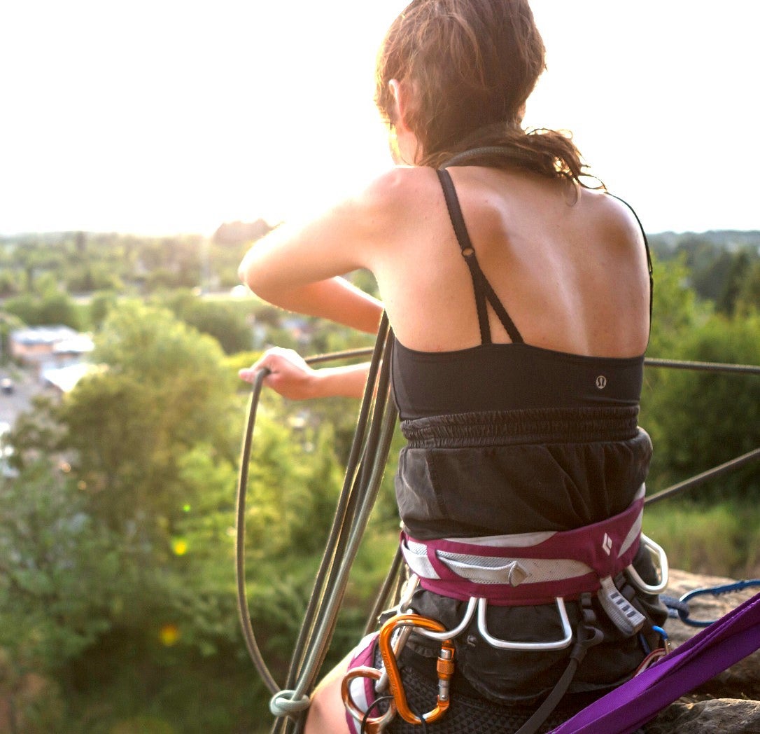 Girl sits on roof with climbing gear on