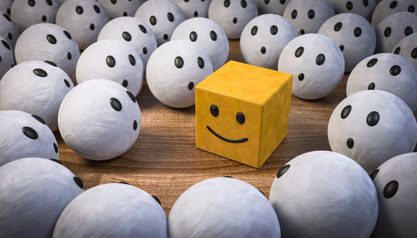 Digital art of a yellow black with a smiley face surrounded by white spheres with uniform looks of awe on their "faces."