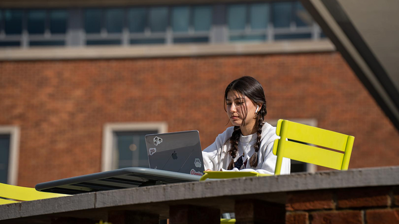 student on laptop outside in erb memorial union on a sunny day studying