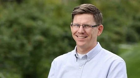 vice provost grant schoonover smiling in a light blue shirt and wearing eyeglasses outside