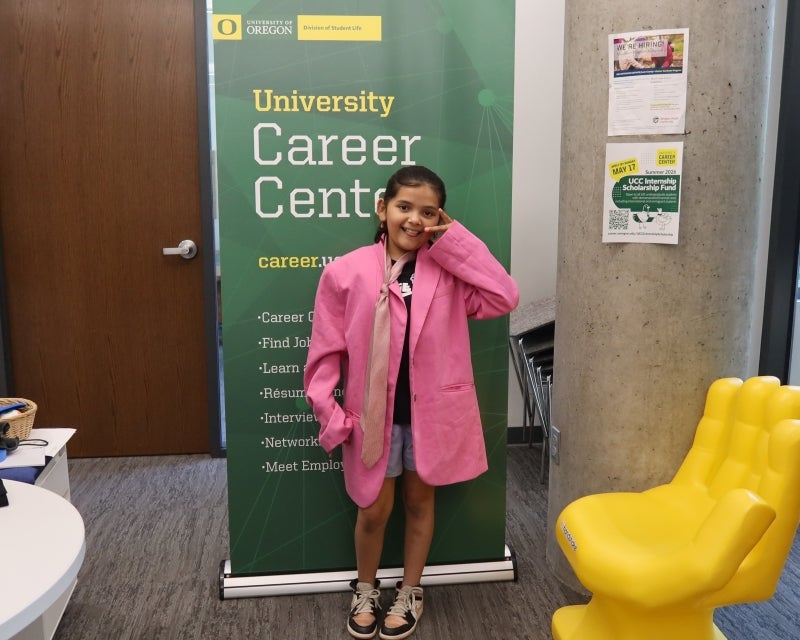 girl in oversized pink blazer in front of sign for career center