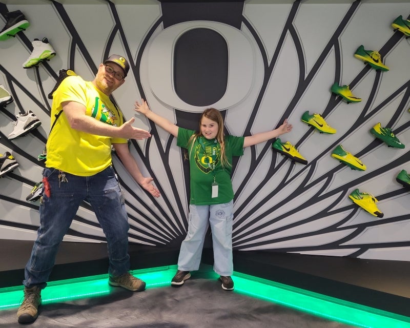 kid spreading arms in front of wall of shoes