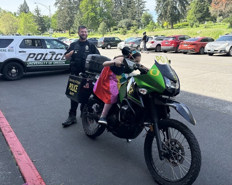 kid on UOPD motorcyle with officer and police car