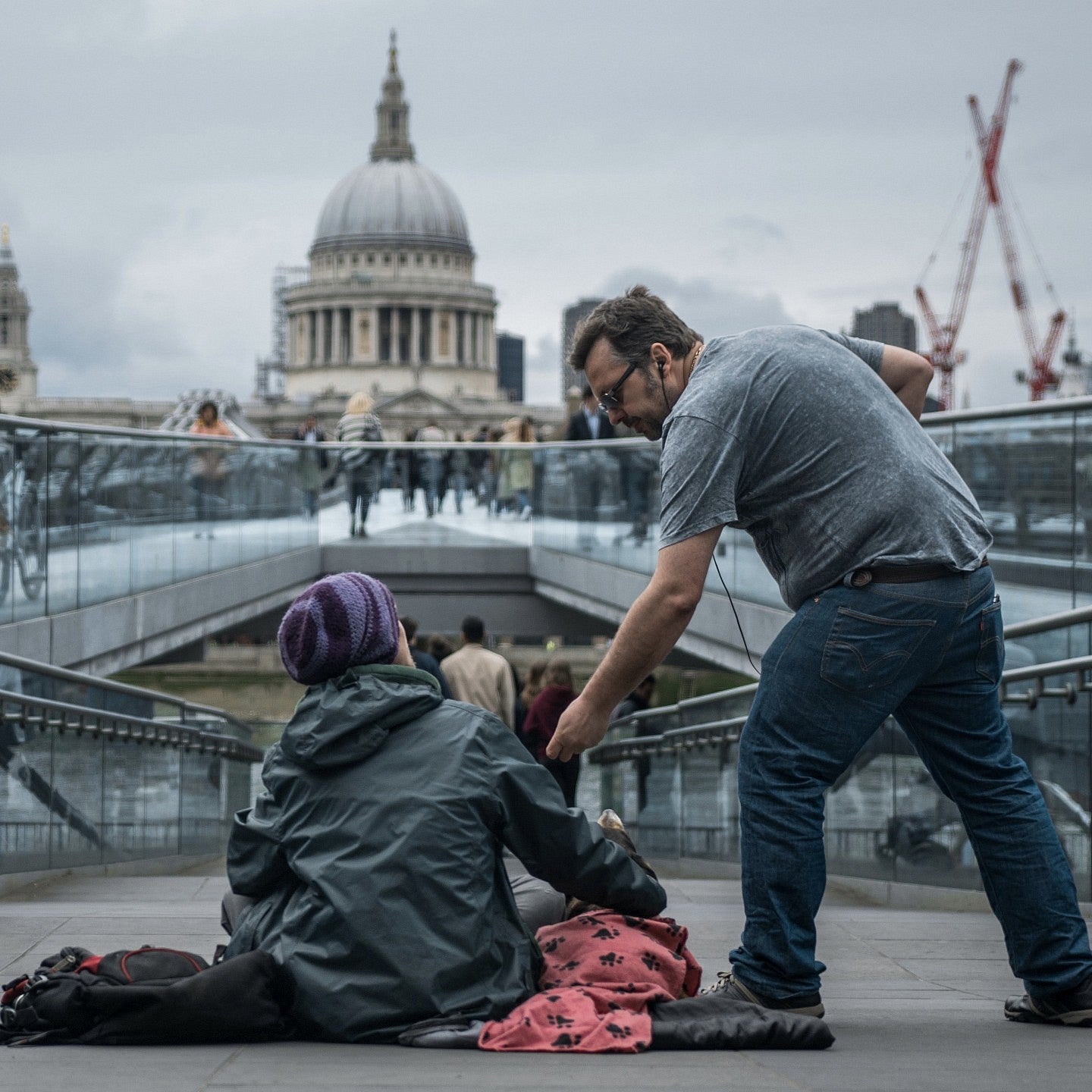 A man offering help to a homeless woman on the streets of London