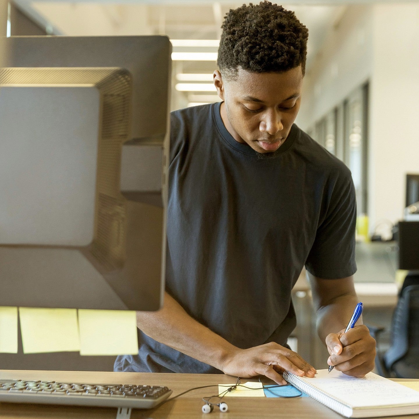 A male student taking notes from a computer.