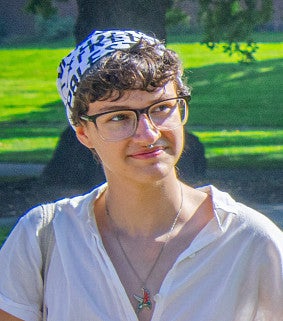 Madelyn Engler has dark hair, glasses and wears a head scarf