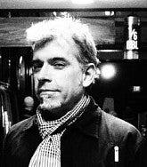 Steven Brence. He has short white hair and goatee and wears a scarf. Photo is black and white.