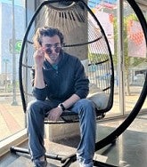 Mac McCarty sits in a hanging chair and has sunglasses