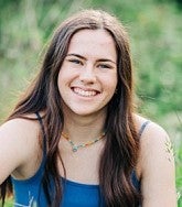 Bella Albiani has long brown hair and wears a blue tank top