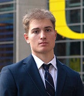 Kimball Weeks has short blonde hair and wears a suit and tie