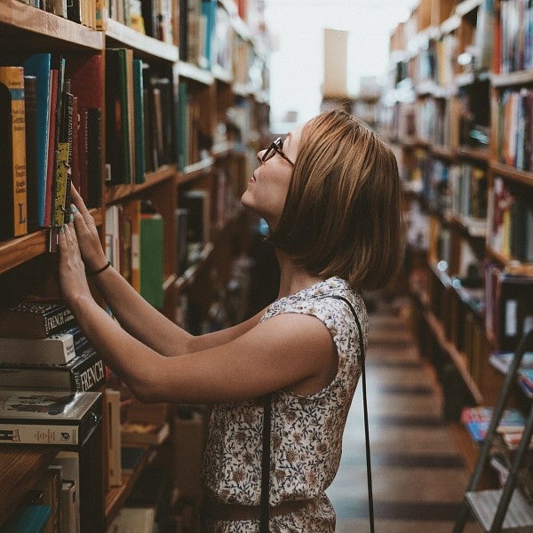 A female student looking for a book on a library bookshelf