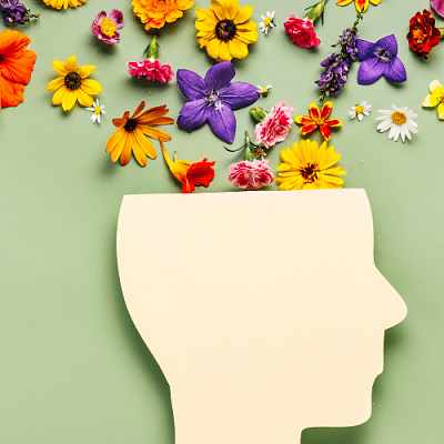 Profile silhouette of a head with flowers exploding from the cut open top.