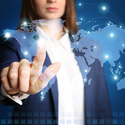 Woman in a navy suit touching a transparent world map between her and the camera