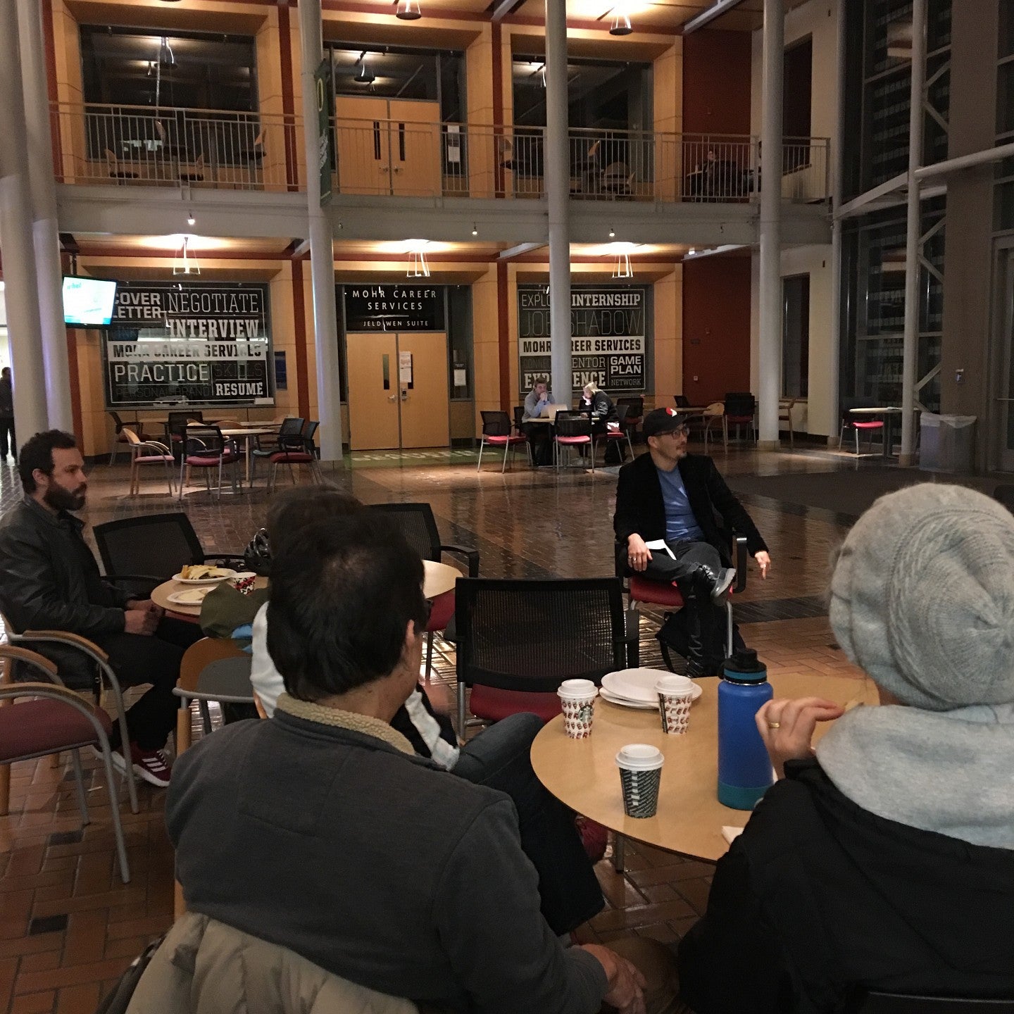People seated at tables talking with a man