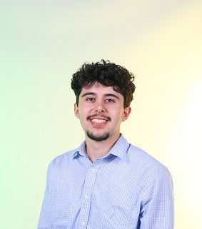 Young man with dark hair, moustache, and goatee, wearing a light blue button up shirt 