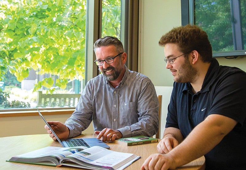 Student sits with academic advisor at table getting advising support