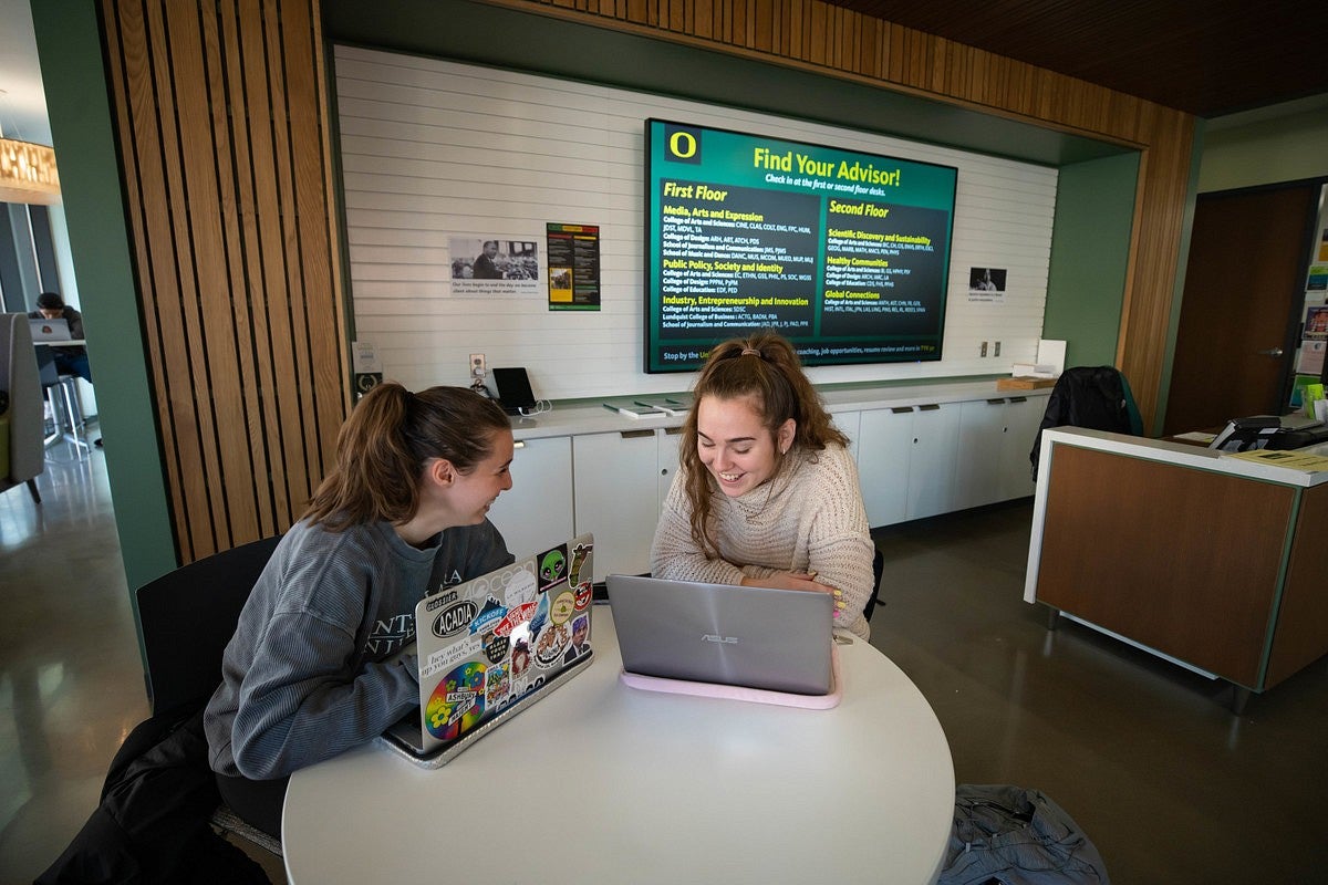 Two students sitting and talking at a table in Tykeson Hall's Advising Office