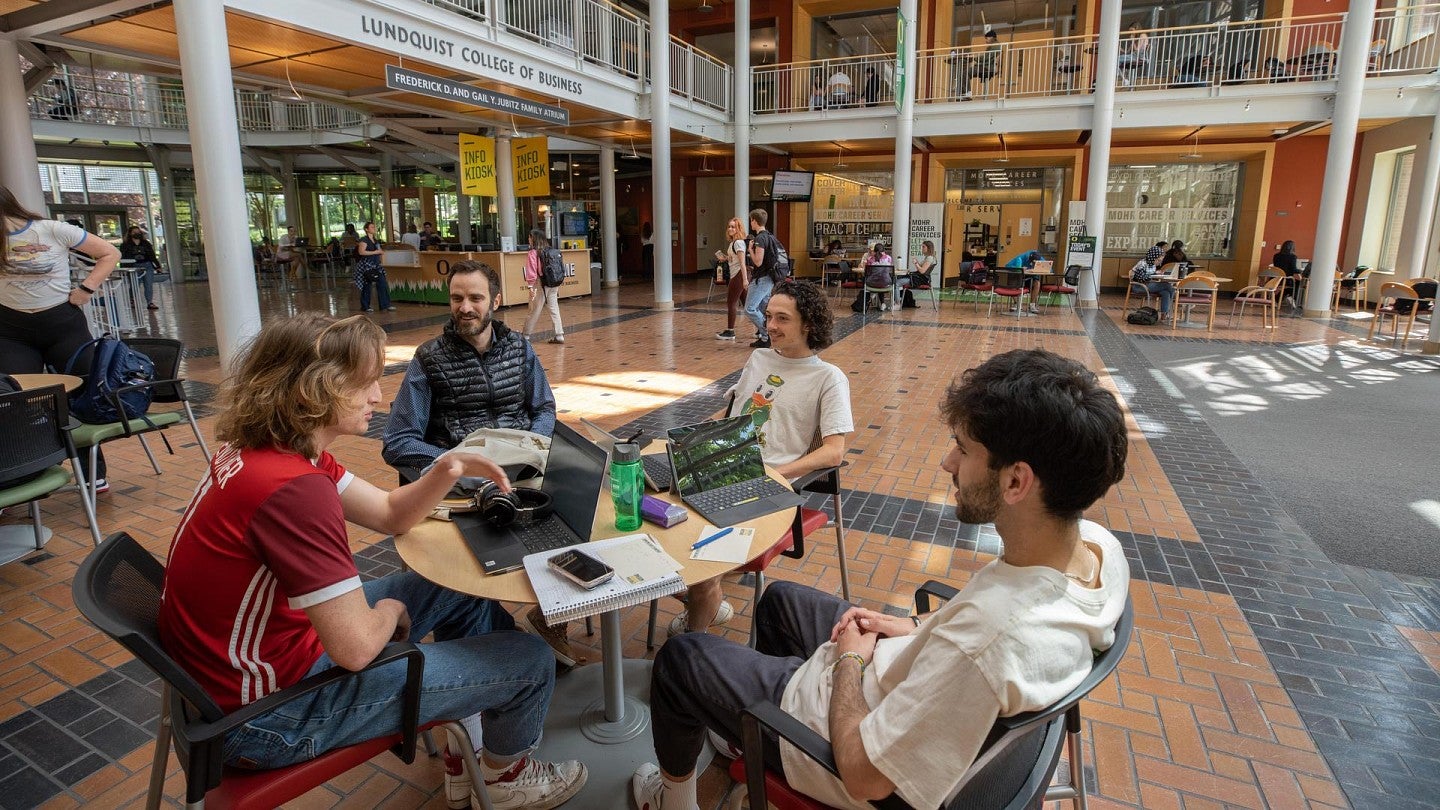 students in lunquist college of business sitting at a table and talking to one another