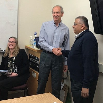 Bob Choquette smiling and shaking Jayanth Banavar's hand while accepting the UDL award.