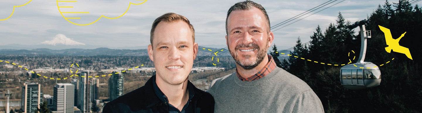 Photo of Banning Hendriks, MBA ’19, (left) and his husband Chris Hamel (right) looking at the camera and smiling with the Portland, Oregon, skyline behind them.