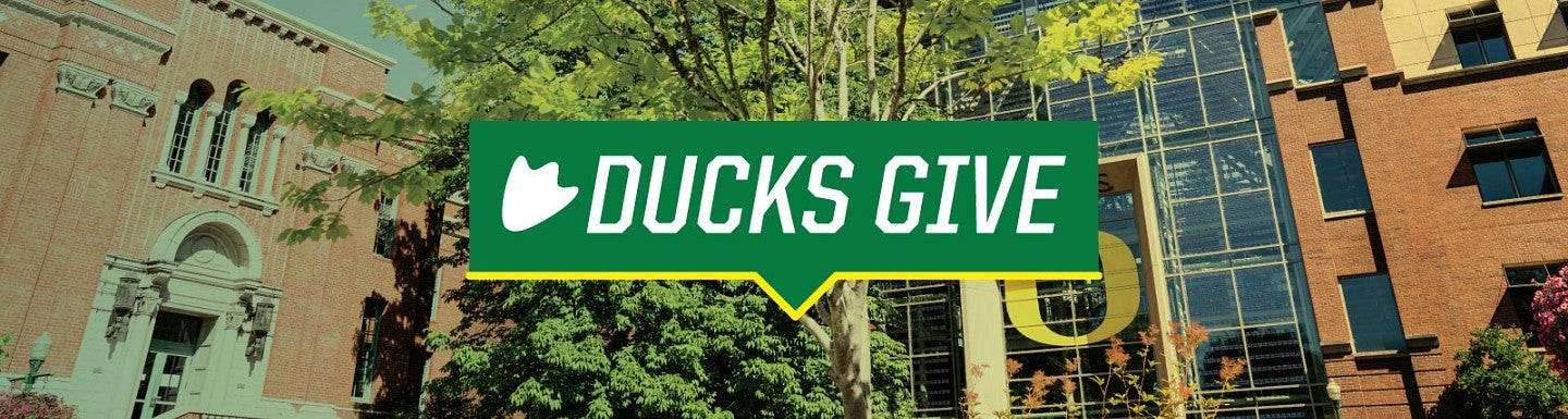 DucksGive logo against a background image of the Lillis Business Complex