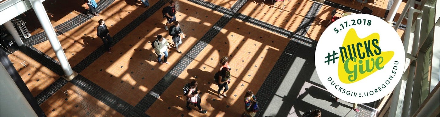 Ducks Give logo against a background of the Lillis atrium