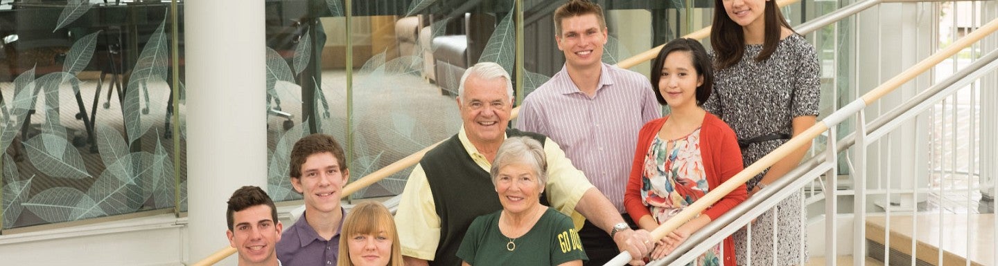 Gerry and Marilyn Cameron and others pose for a photo on a staircase in the Lillis atrium