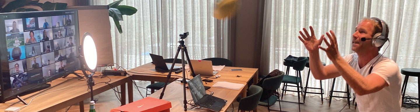 A man throws a football while broadcasting on Zoom