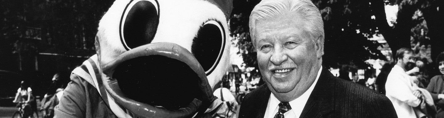 Charles Lundquist stands next to the Oregon Duck mascot in a black and white photo