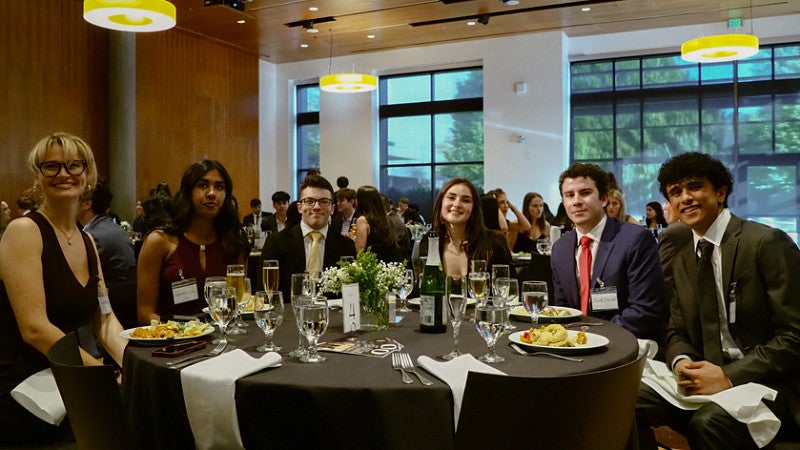 Members of the Lundquist Student Organization Committee sit at a table during the group's end-of-the-year gala