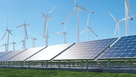 A group of wind turbines behind a row of solar panels