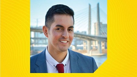 Oscar Arana stands in front of the Portland cityscape