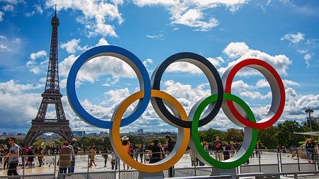 A statue of the Olympic rings in front of the Eiffel Tower