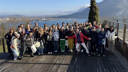 SPM students pose for a group photo in front of a lake with mountains further out