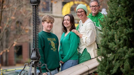 Kathleen, Brad, Maya, and Lukas McLeroy stand together on a stairwell in front of the Lillis Business Complex