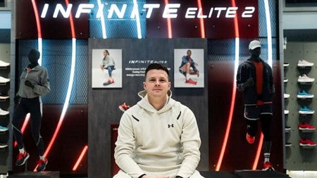 Jonathan Hutnyan sits in front of a display of athletic gear